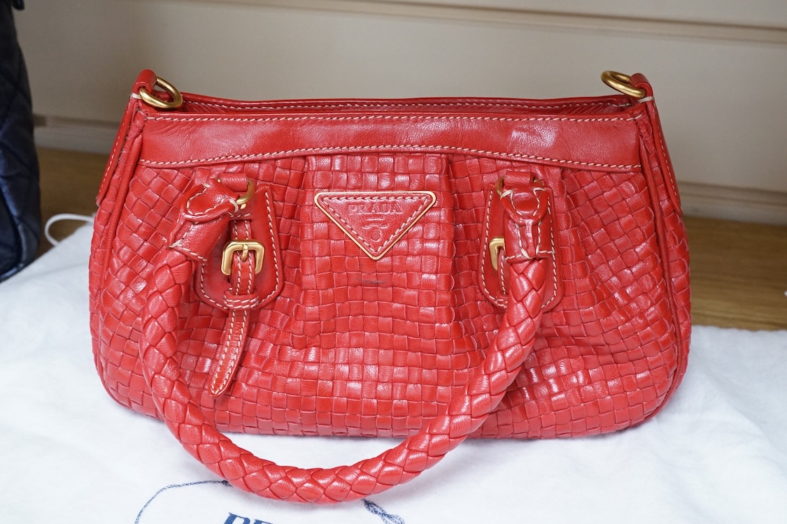 A Prada red braided leather handbag with shoulder strap, authenticity card and dust cover, 25cm wide, Provenance: Purchased by the vendor in Selfridges